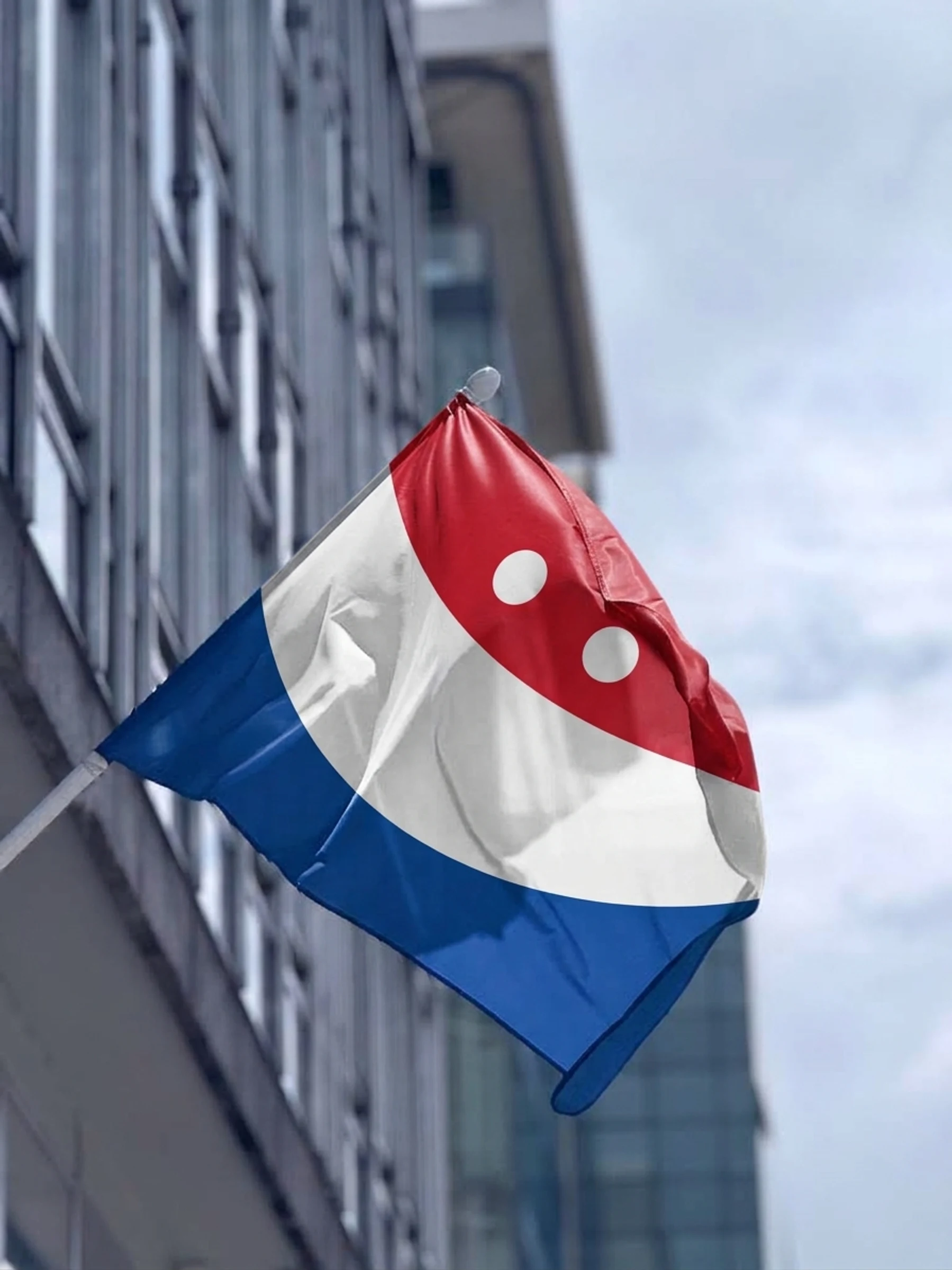 Glimvlag with its red, white and blue smile on a building facade pole (digital composite)