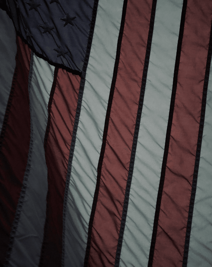 Better Flags | CiCLO Flags | Close-up of a wrinkled American flag showing red and white stripes and a blue section with stitched black stars.