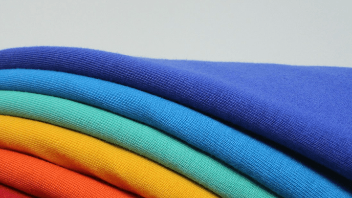 Better Flags | CiCLO Flags | Stack of folded fabric in vibrant colors including blue, teal, yellow, and orange.